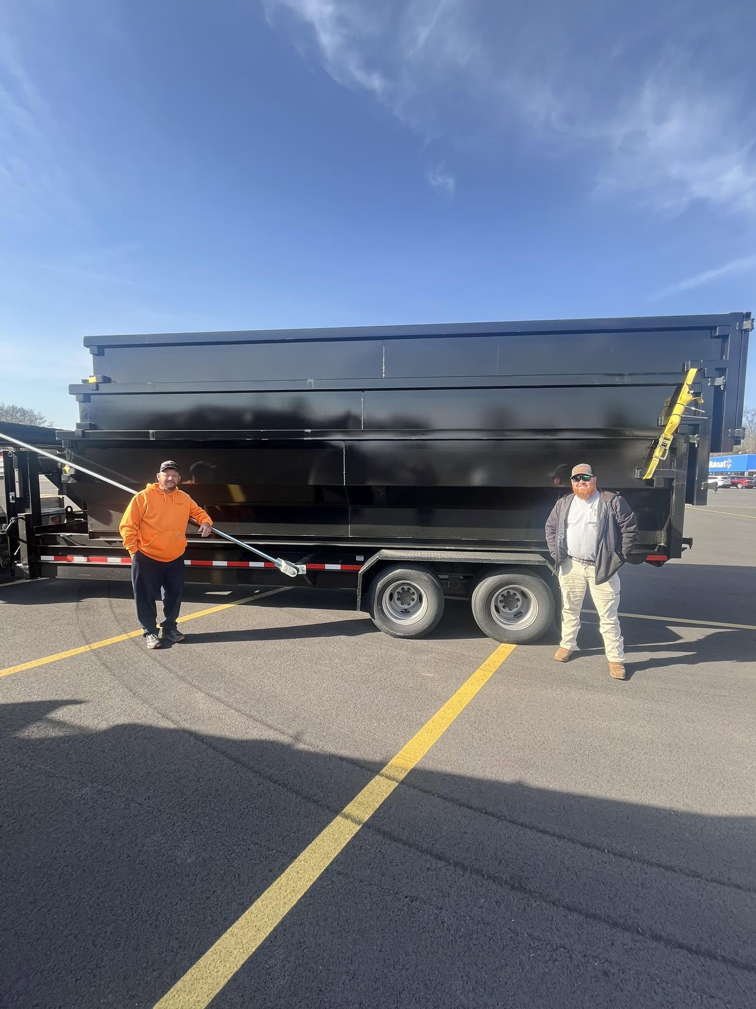 Two people standing in front of a black Dumpster Daddy dumpster